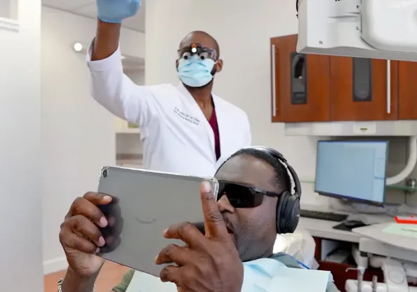 Dr. Ntekim with a relaxed patient wearing headphones